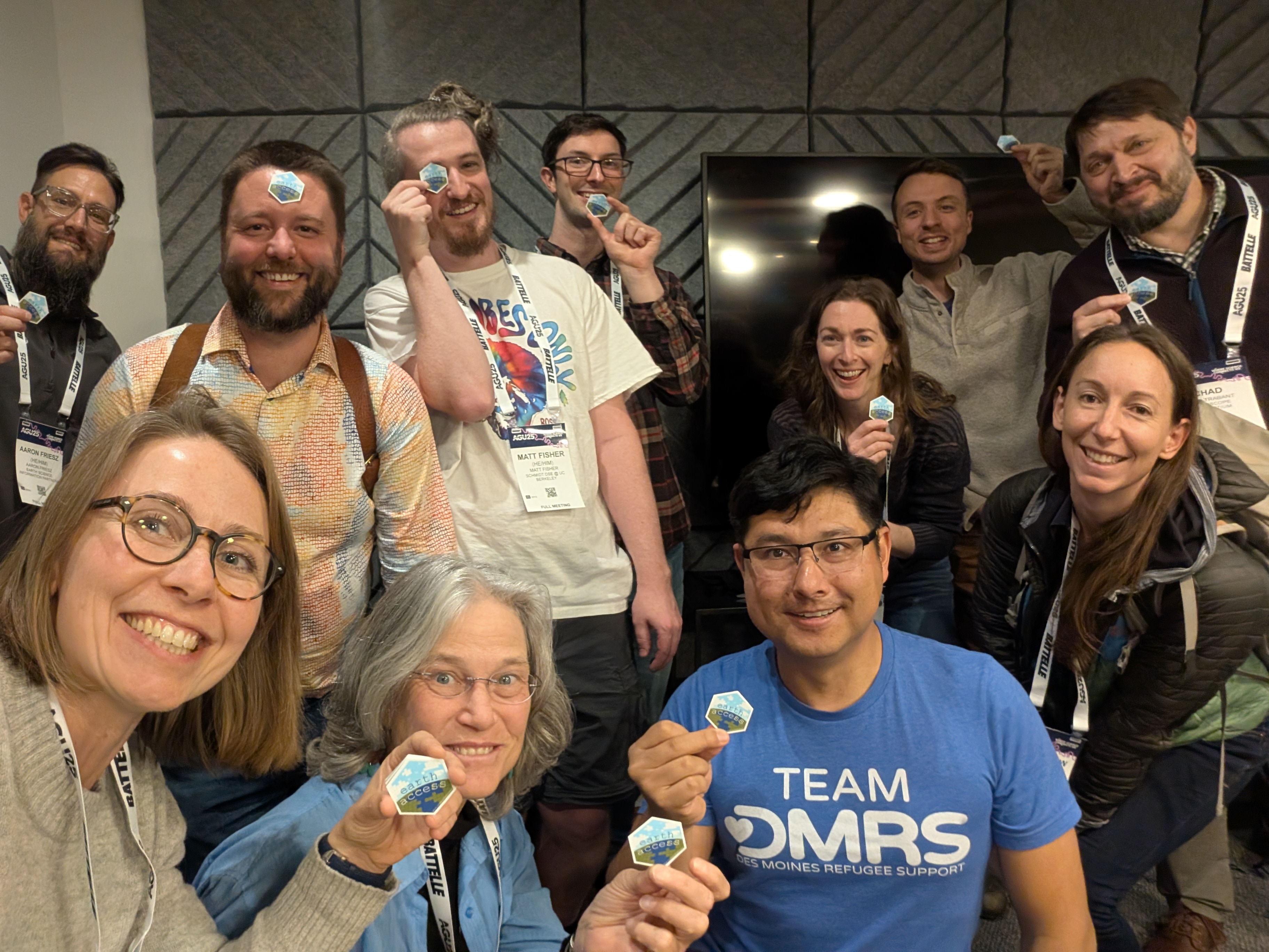 photo of eleven smiling women and men holding up hexagonal stickers
